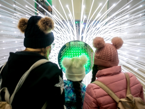 Three people stand in front of light sculpture
